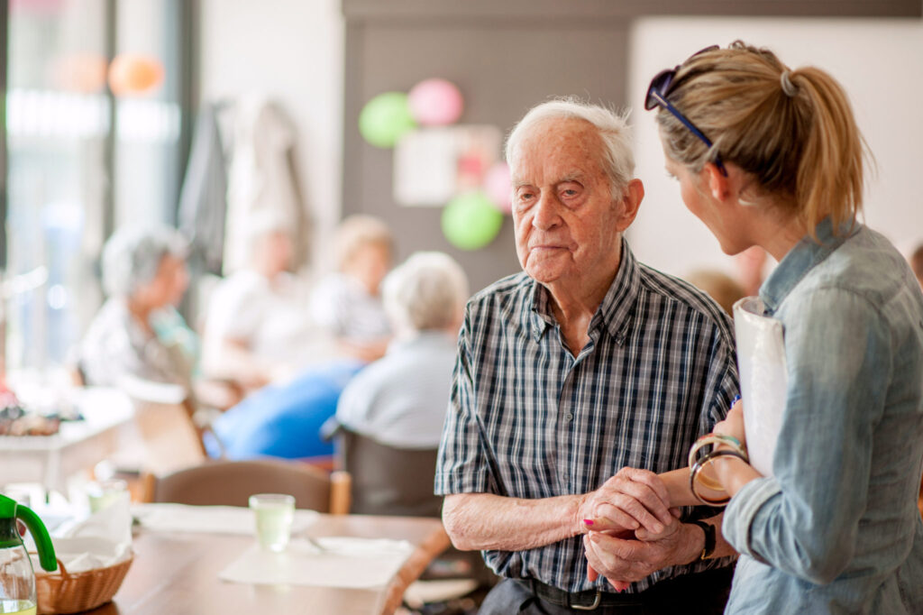 Assistant In The Community Center Giving Advice To A Senior Man Assistant In The Community Center Giving Advice To A Senior Man